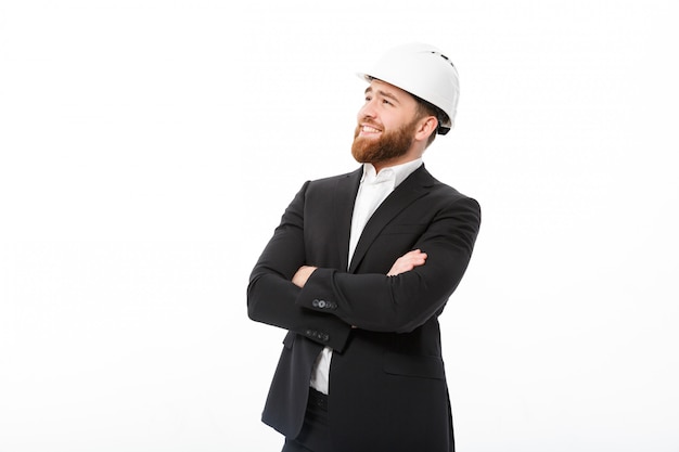 Smiling bearded business man in protective helmet holding crossed arms