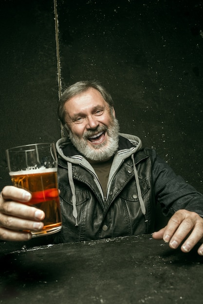 Free photo smiling bearded male drinking beer in pub