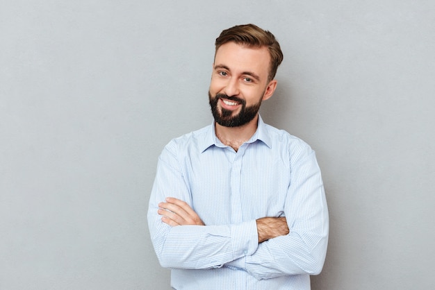 Smiling bearded man in business clothes with crossed arms