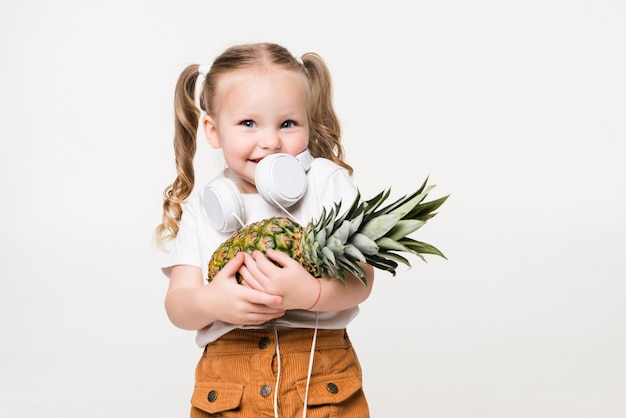 Smiling beatiful little girl holding pineapple