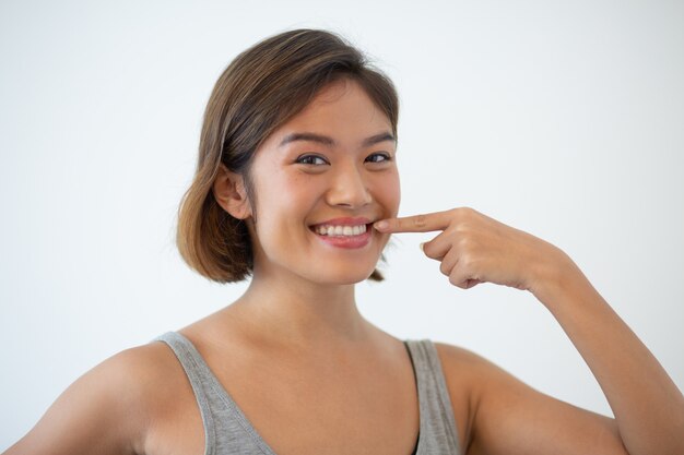 Smiling beautiful Asian woman pointing at her teeth