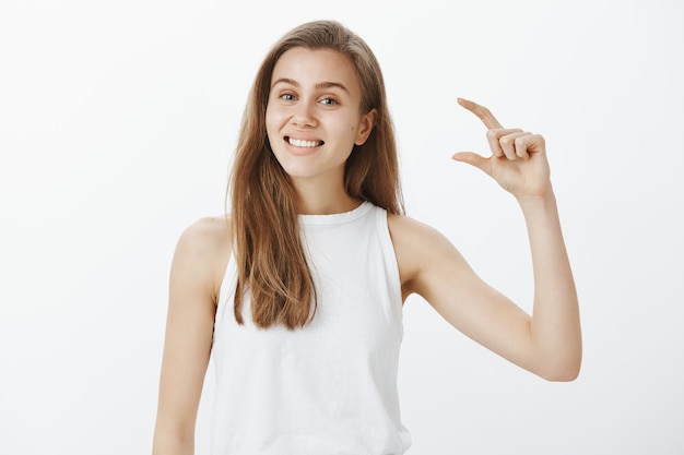 Smiling beautiful female student showing something small, tiny object or little