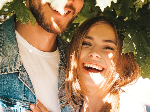 Smiling beautiful girl and her handsome boyfriend posing in the street near tree.