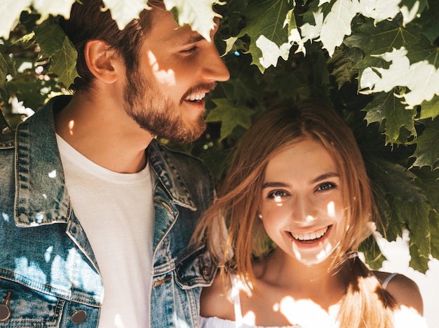 Smiling beautiful girl and her handsome boyfriend posing in the street near tree.