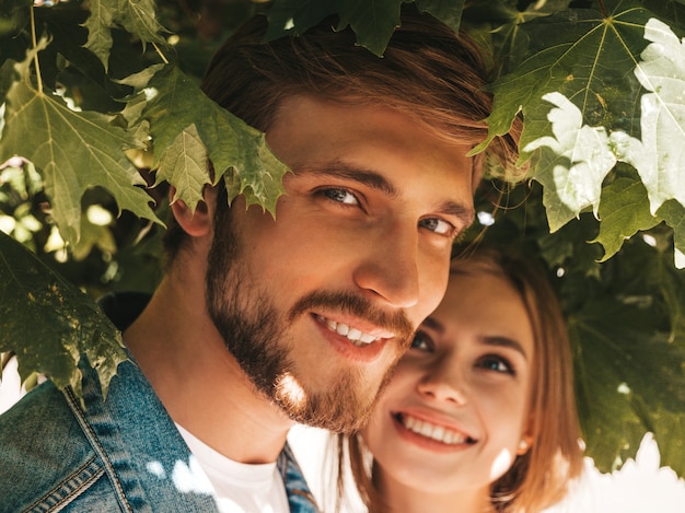 Smiling beautiful girl and her handsome boyfriend posing in the street near tree. 