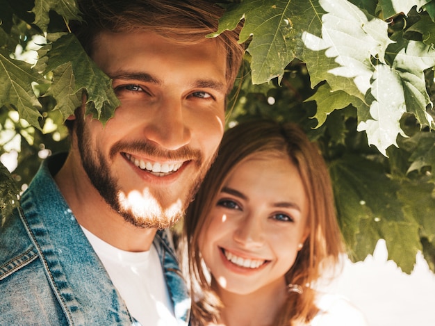 Free photo smiling beautiful girl and her handsome boyfriend posing in the street near tree.