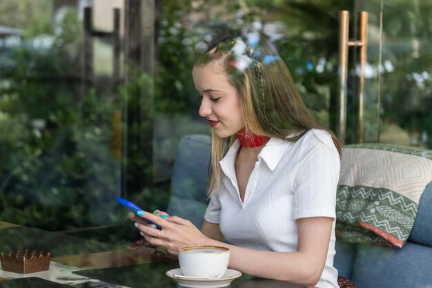 Smiling beautiful lady sitting at the restaurant and playing with her phone