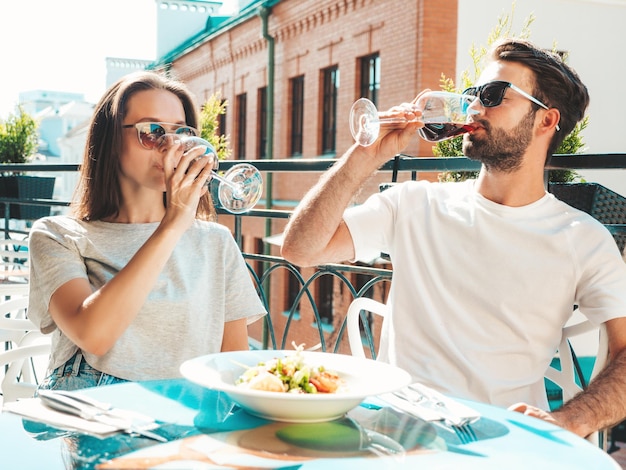 Smiling beautiful woman and her handsome boyfriend Happy cheerful family Couple cheering with glasses of red wine at their date in restaurant They drinking alcohol at veranda cafe in the street