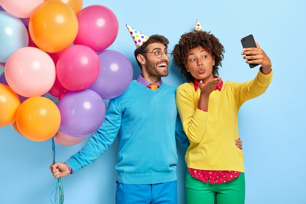 Free photo smiling beautiful young couple at a party posing with balloons