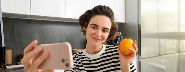 Free photo smiling beautiful young woman taking selfie with fresh yellow pepper food blogger taking selfie with