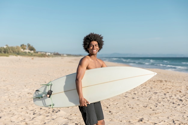 Free photo smiling black man with surfboard on seashore