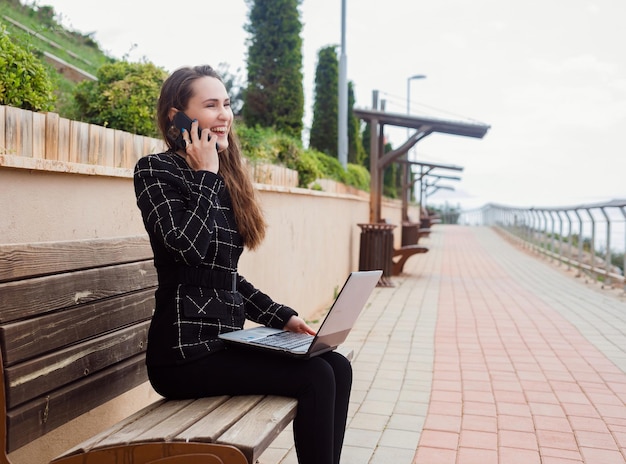 Smiling blogger girl is talking on smartphone in park