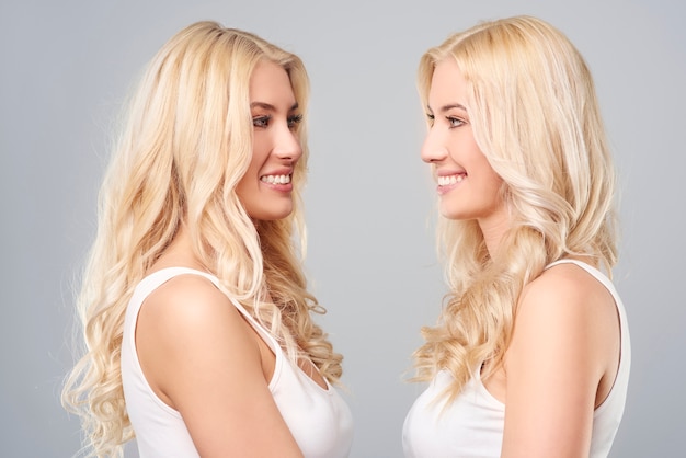 Smiling blonde twins standing face to face
