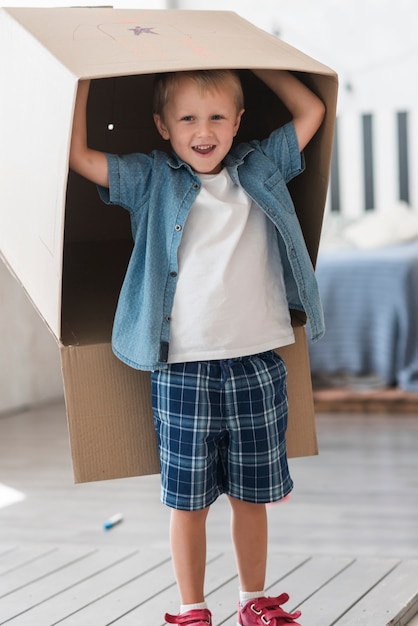 Smiling boy standing with cardboard box over his head