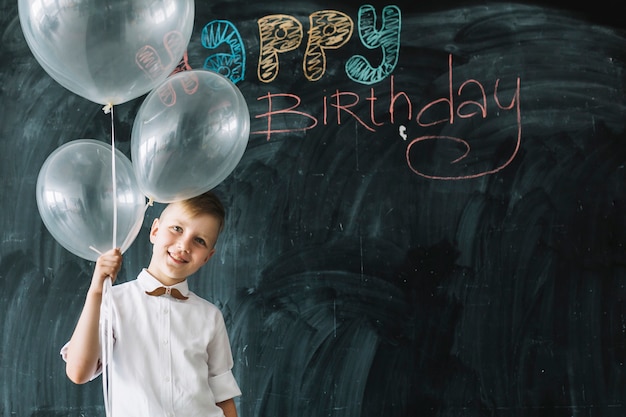 Free Photo smiling boy with balloons near happy birthday writing