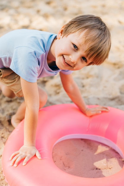 Free photo smiling boy with swimming ring on sand