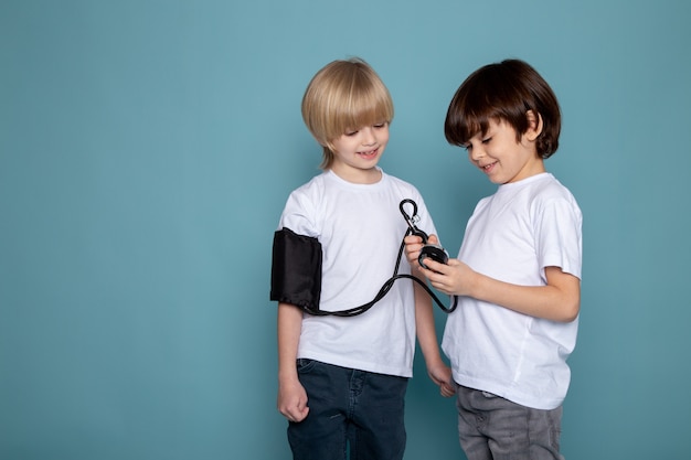 Smiling boys one measuring others pressure on blue desk