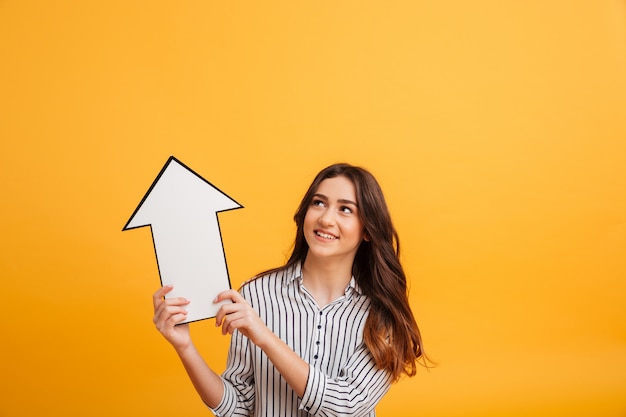 Free photo smiling brunette woman in shirt pointing with paper arrow up