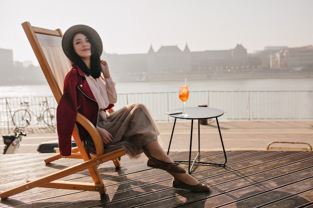 Free photo smiling brunette woman sitting on recliner enjoying vacation in europe