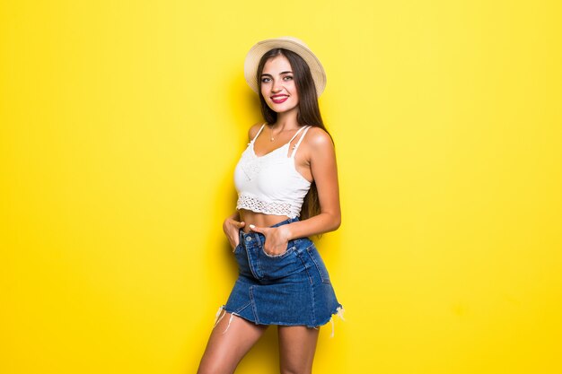 Smiling brunette woman in sweater posing with crossed arms over yellow wall