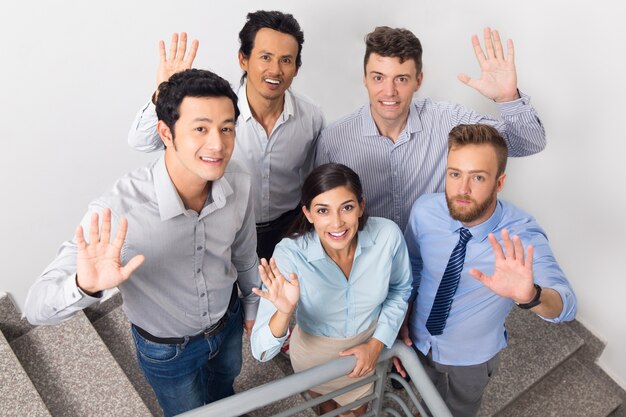 Smiling Business People Waving on Office Stairway