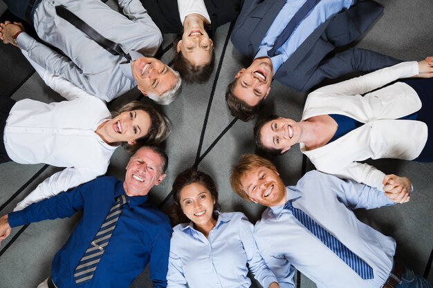 Free Photo smiling business team lying on floor in circle