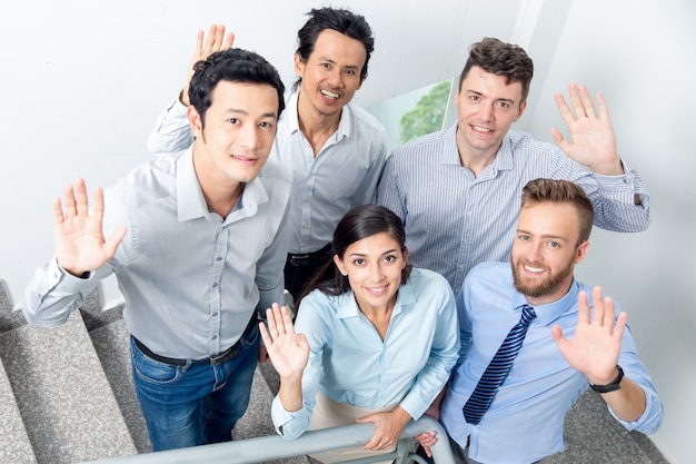 Smiling Business Team Waving on Office Stairway