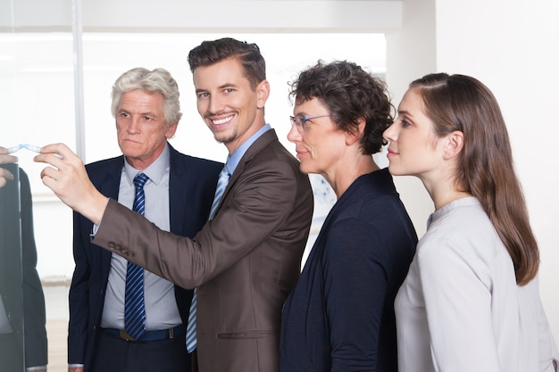 Free photo smiling businessman drawing on flipchart for team