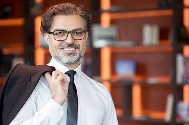 Free photo smiling businessman holding jacket on shoulder