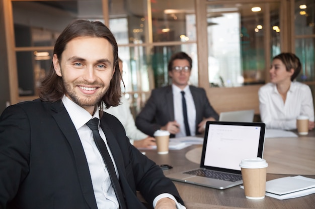 Free photo smiling businessman manager in suit looking at camera at meeting