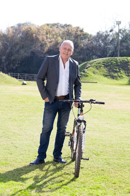 Smiling businessman posing with his bicycle in the park