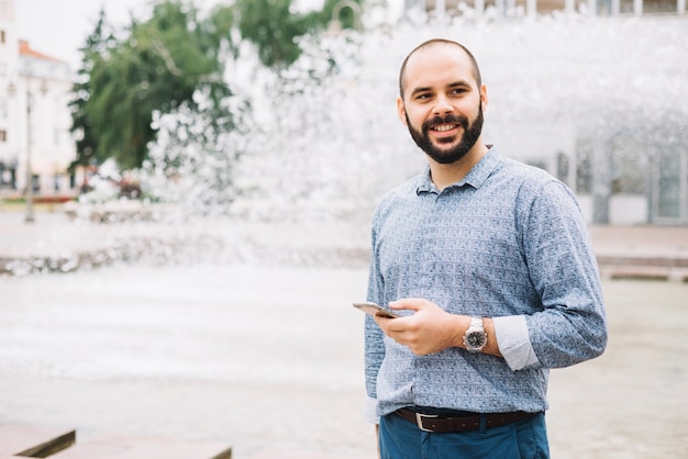 Smiling businessman with phone in downtown