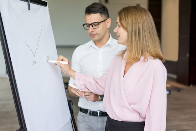 Free photo smiling businesswoman drawing diagram to male colleague.