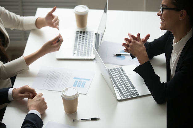 Smiling businesswoman enjoying talk with colleagues during teamwork with laptops