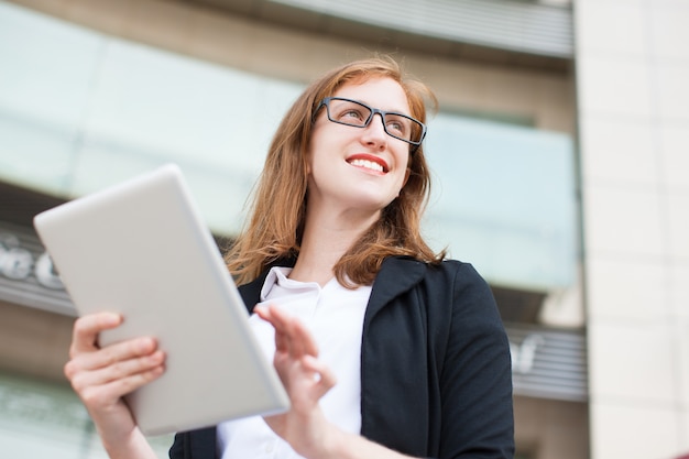 Free photo smiling businesswoman using touchpad outdoors