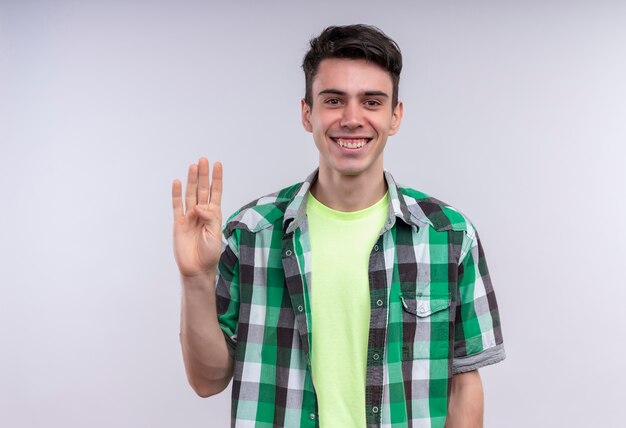 Smiling caucasian young guy wearing green shirt showing four on isolated white background