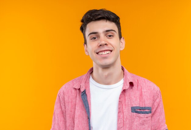 Smiling caucasian young guy wearing pink shirt on isolated orange background