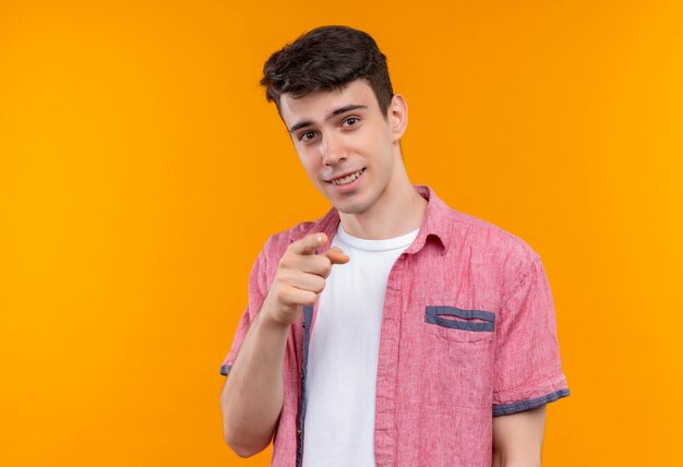 Smiling caucasian young guy wearing pink shirt showing you gesture on isolated orange background