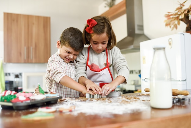 Smiling children decorating christmas cookies in the kitchen