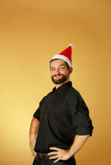 Free photo smiling christmas man wearing a santa hat on the orange studio background