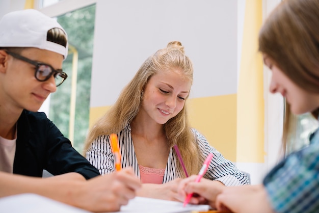 Free photo smiling classmates writing at desk