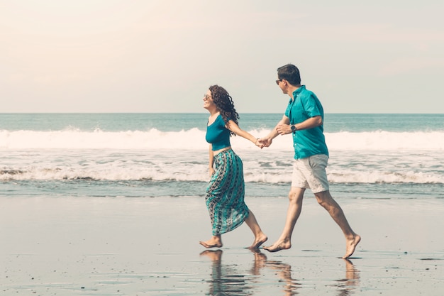 Smiling couple barefoot walking along beach