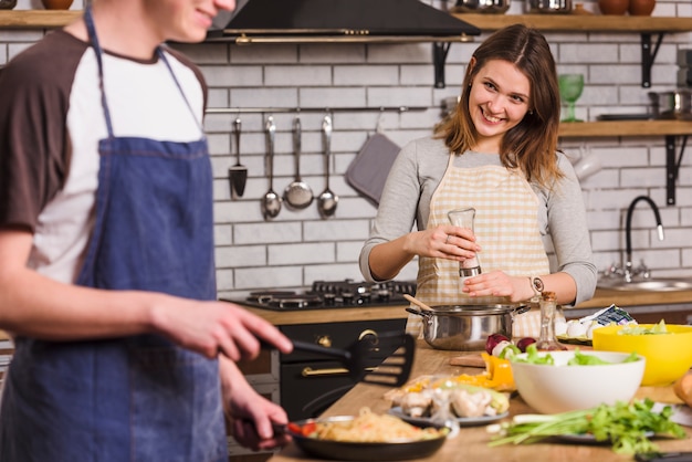 Smiling couple cooking dishes together 