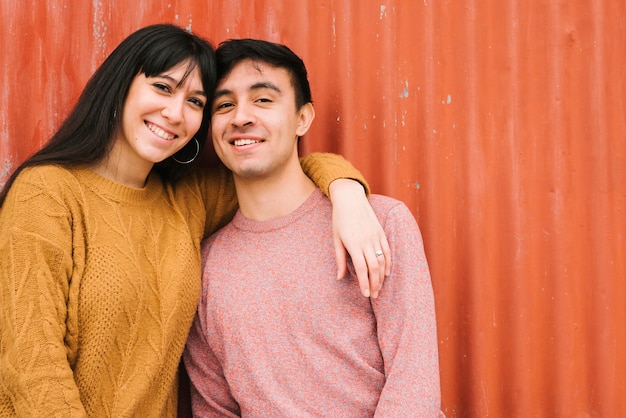 Smiling couple cuddling by wall