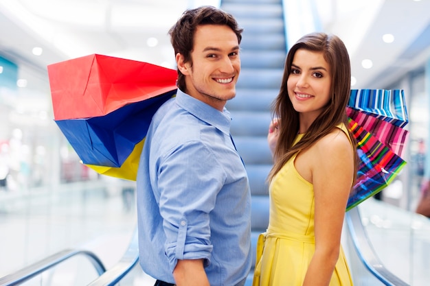 Smiling couple on escalator in shopping mall