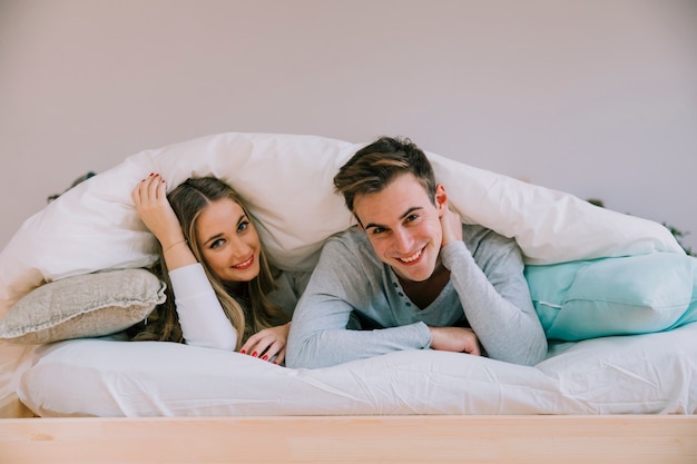 Smiling couple lying under blanket