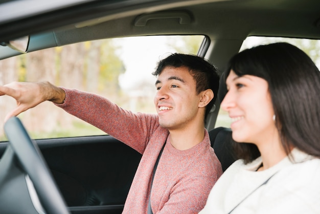 Smiling couple pointing and looking ahead in car