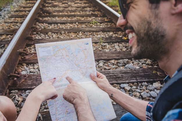 Free photo smiling couple pointing at map on train tracks