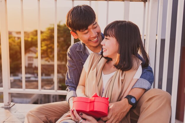 Smiling couple sitting on the floor with a red gift