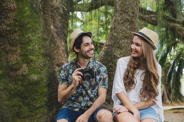 Smiling couple sitting on tree root